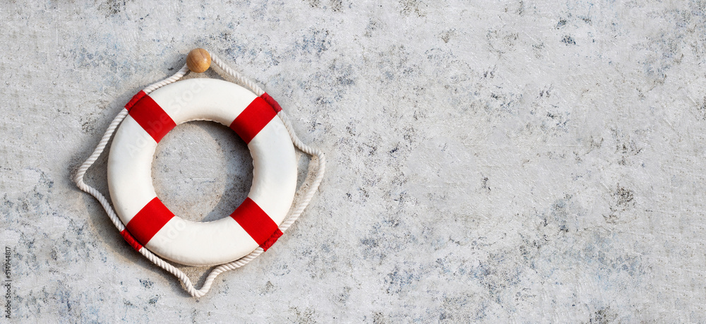 Naklejka premium Lifebuoy on cement wall background. Copy space