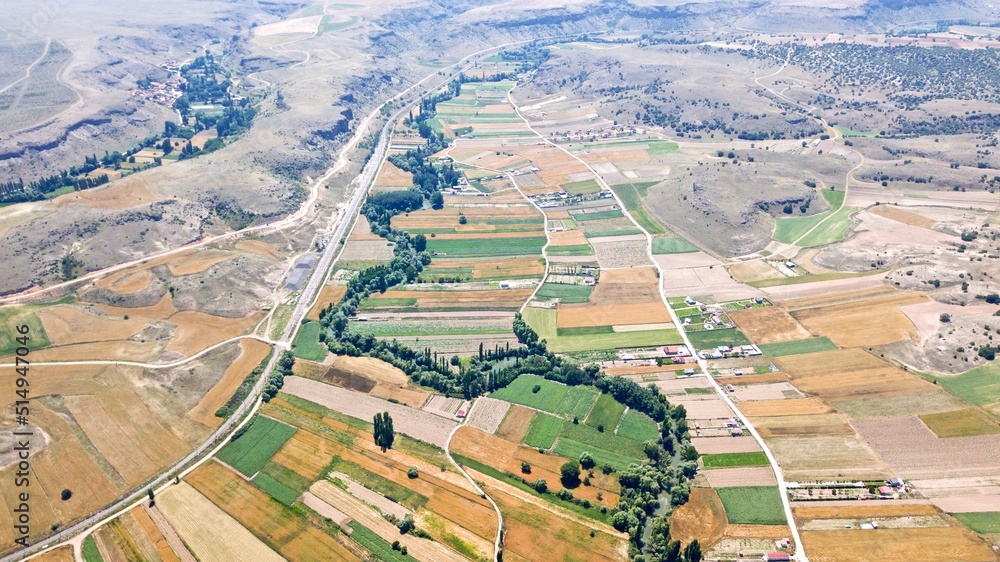 Aerial view of the agricultural fields, mountains and river in the countryside.