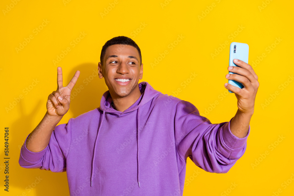 Portrait of handsome trendy cheerful guy taking selfie showing v sign blog influencer isolated over bright yellow color background Portrait of handsome trendy cheerful guy taking selfie showing v sign blog influencer isolated over bright yellow color background