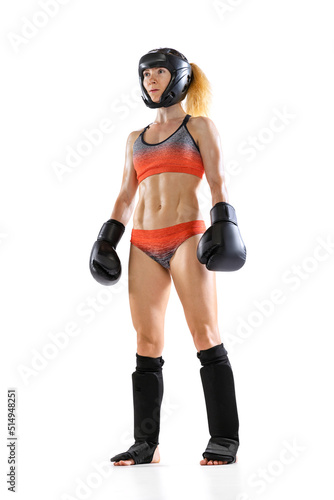 Sportive woman, female professional kickboxer in sports gloves and protective helmet posing isolated on white background. Sport, achievements concept © master1305