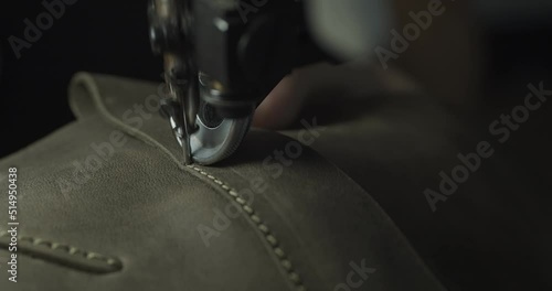 Tailor works on sewing machine in private leather craftshop, making shoes in process. male seamstress sewing leather shoes in leather workshop in 4k