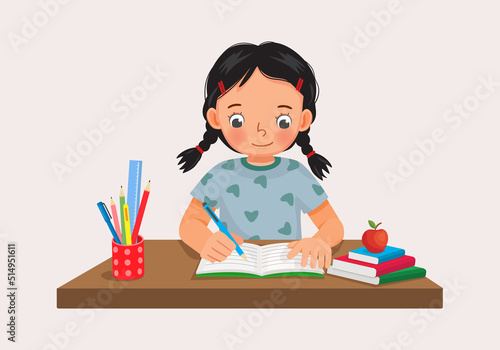Cute little girl sitting on the desk studying writing on notebook doing her homework at home