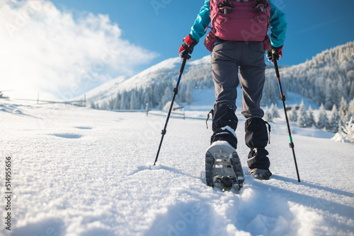Fotografía A woman with a backpack in snowshoes climbs a snowy mountain
