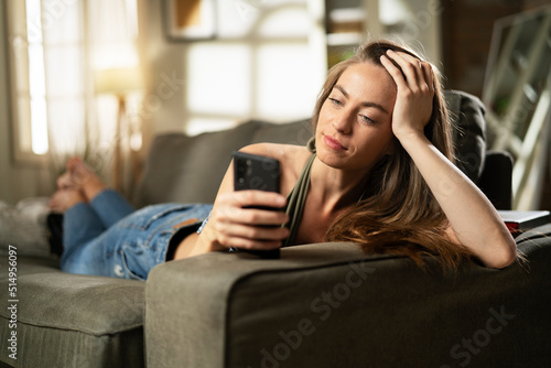 Happy young woman using the phone at home. Excited woman enjoying in the living room..