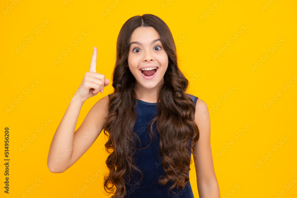 Excited face, cheerful emotions of teenager girl. Portrait of young teenager pointing up with finger, isolated on yellow background. Funny school girl, kid genius, nerd young student. Excited face, cheerful emotions of teenager girl. Portrait of young teenager pointing up with finger, isolated on yellow background. Funny school girl, kid genius, nerd young student.