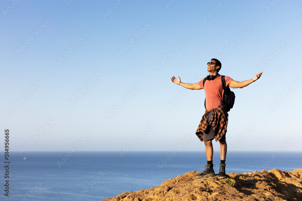 Young man standing on the stone with raised up arms. Tourist man on the top of the mountain. Young man standing on the stone with raised up arms. Tourist man on the top of the mountain.