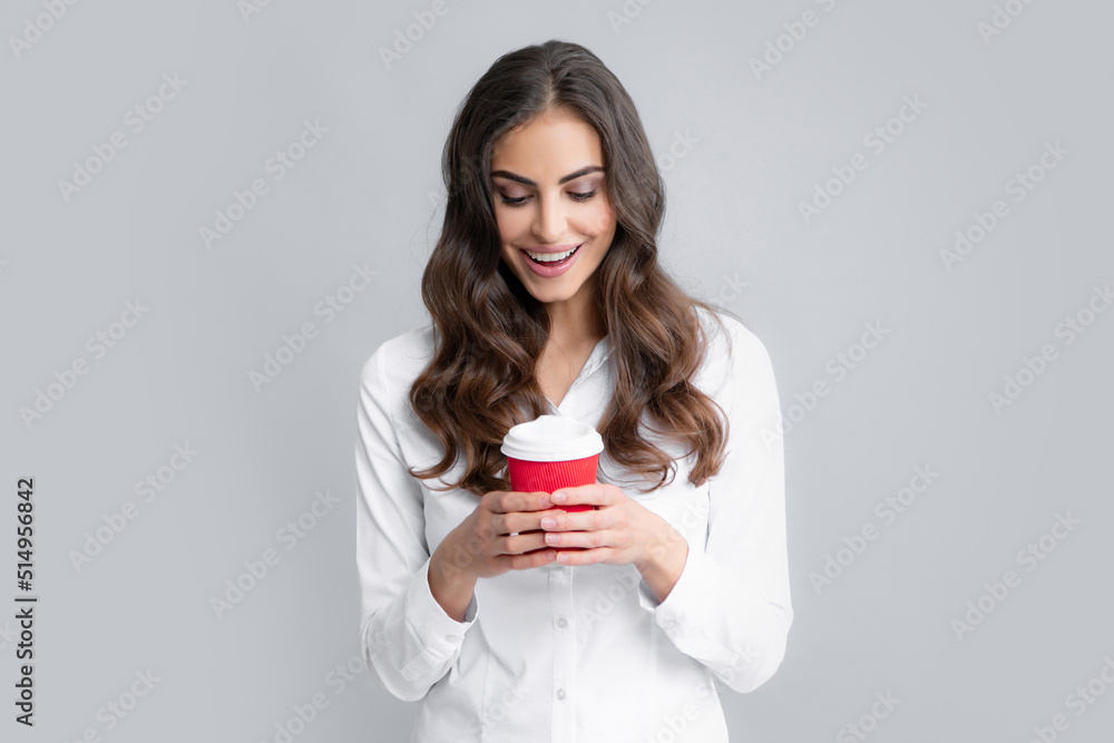 Portrait of a beautiful young woman with a cup of coffee standing on the gray background. Portrait of a beautiful young woman with a cup of coffee standing on the gray background.