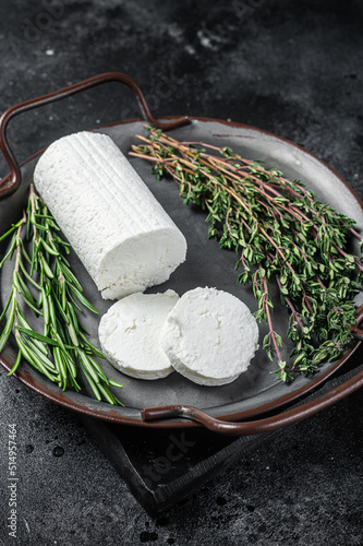 Chevre goat soft cheese with herbs on a tray. Black background. Top view