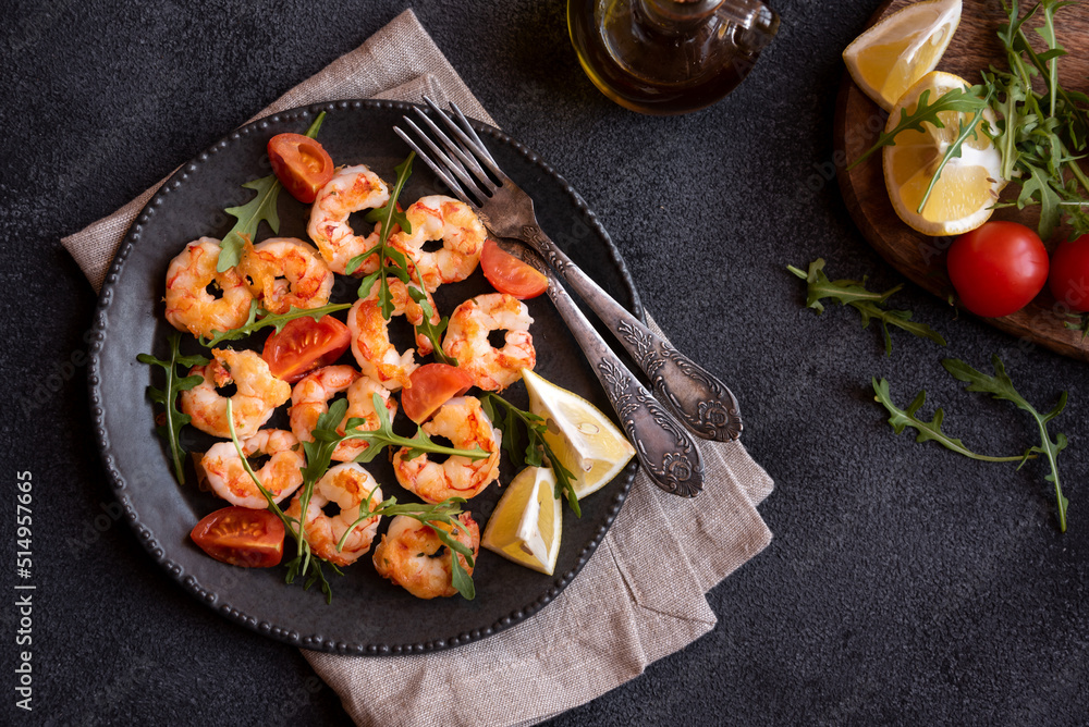 Roasted shrimps with tomatoes and arugola on black plate Roasted shrimps with tomatoes and arugola on black plate