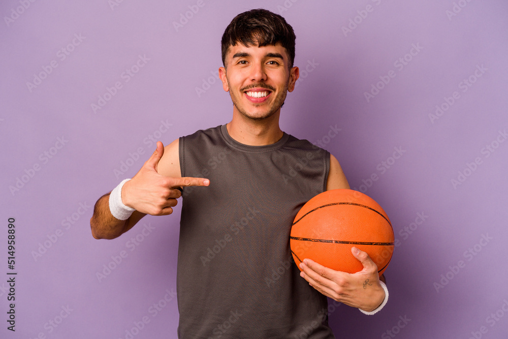 Young hispanic basketball player man isolated on purple background person pointing by hand to a shirt copy space, proud and confident Young hispanic basketball player man isolated on purple background person pointing by hand to a shirt copy space, proud and confident