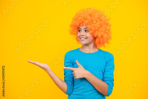 Happy teenager portrait. Teenage girl with yellow wig. Funny child wearing orange curly wig hair. Smiling girl.