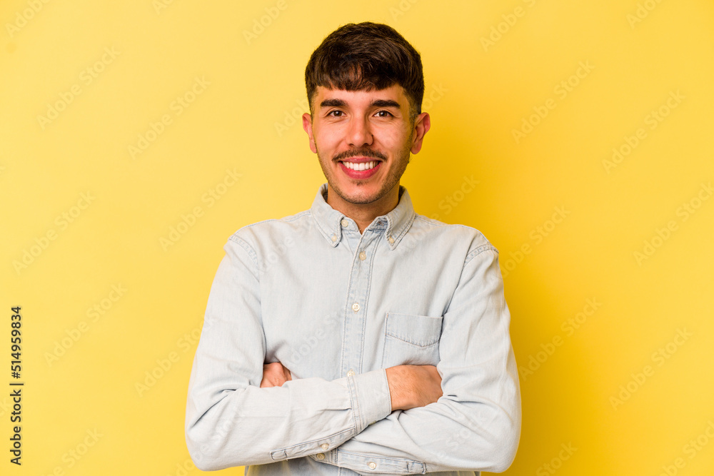 Young caucasian man isolated on yellow background who feels confident, crossing arms with determination. Young caucasian man isolated on yellow background who feels confident, crossing arms with determination.