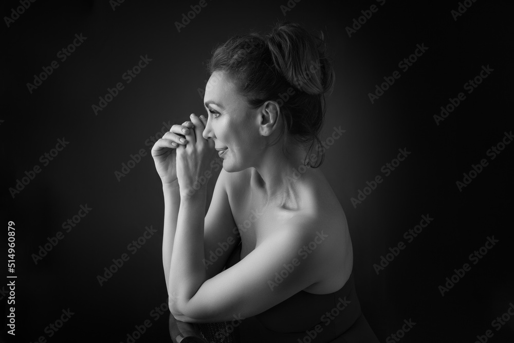 Obraz premium Portrait of a sensual fifty -year -old woman on grey studio background. Monochrome shot.