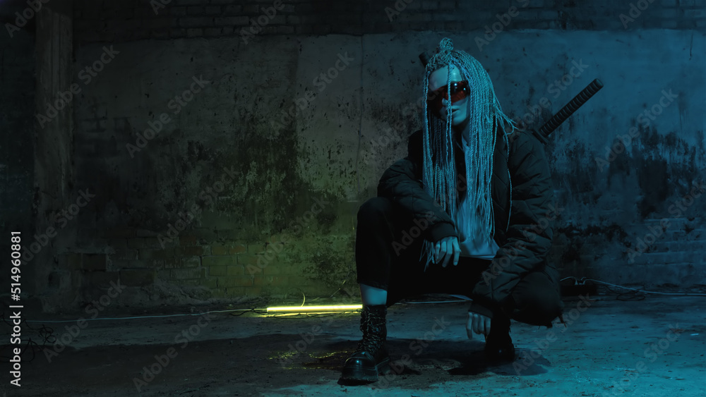girl with dreadlocks and katanas in red glasses posing against a neon brick wall