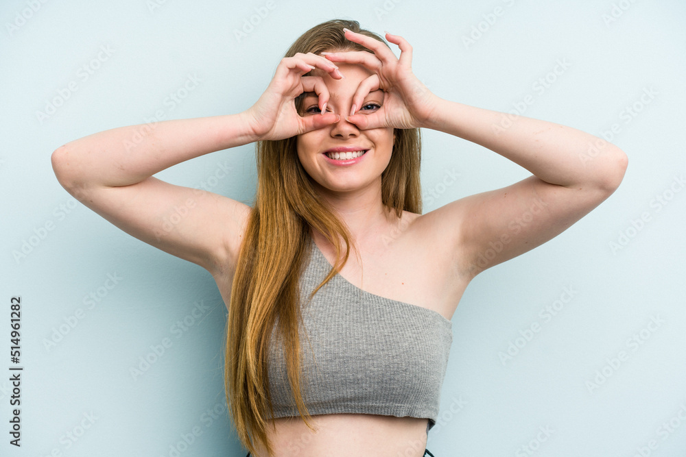 Young caucasian woman isolated on blue background showing okay sign over eyes Young caucasian woman isolated on blue background showing okay sign over eyes