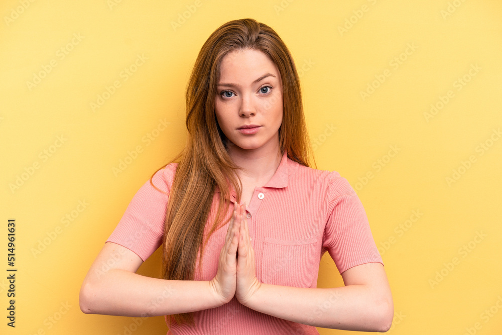 Obraz premium Young caucasian woman isolated on yellow background praying, showing devotion, religious person looking for divine inspiration.