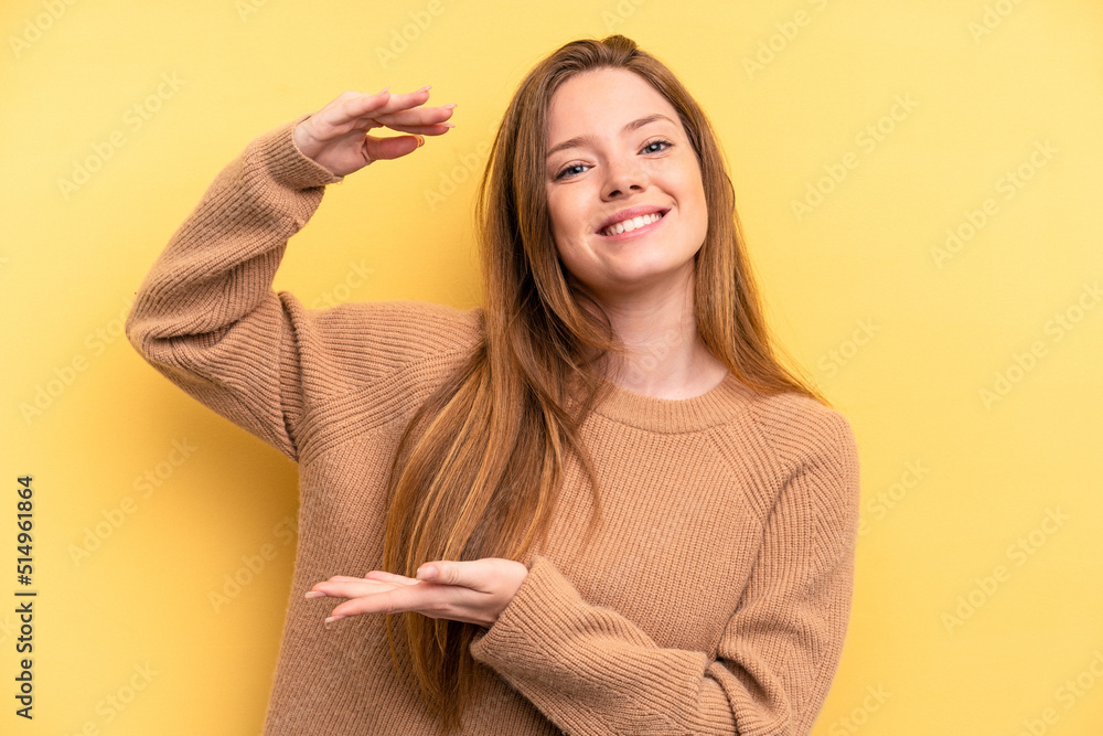 Young caucasian woman isolated on yellow background holding something little with forefingers, smiling and confident. Young caucasian woman isolated on yellow background holding something little with forefingers, smiling and confident.