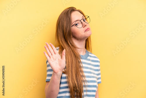 Young caucasian woman isolated on yellow background rejecting someone showing a gesture of disgust.