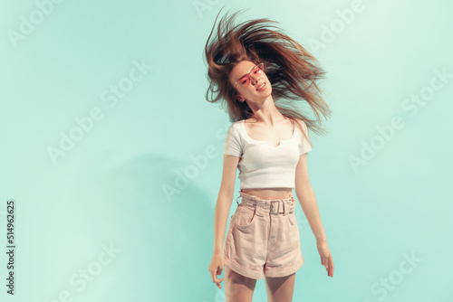 Excited young beautiful girl with long hair posing isolated on light blue color background. Concept of beauty, art, fashion, emotions, youth