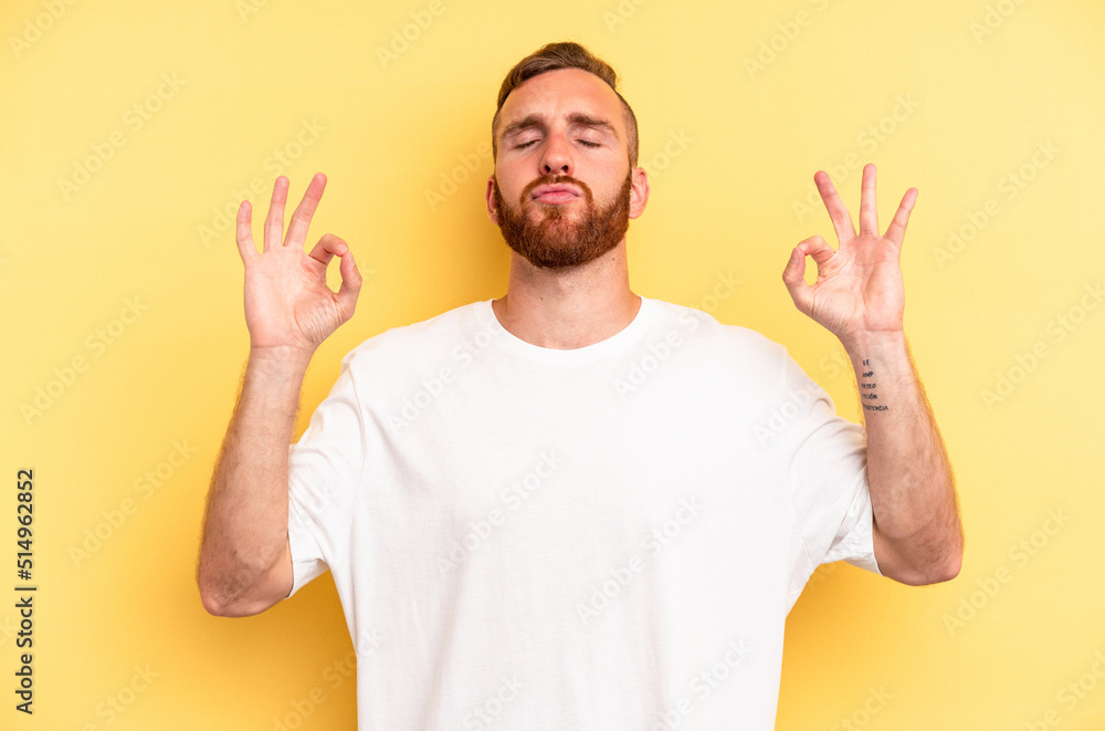 Young caucasian man isolated on yellow background relaxes after hard working day, she is performing yoga. Young caucasian man isolated on yellow background relaxes after hard working day, she is performing yoga.