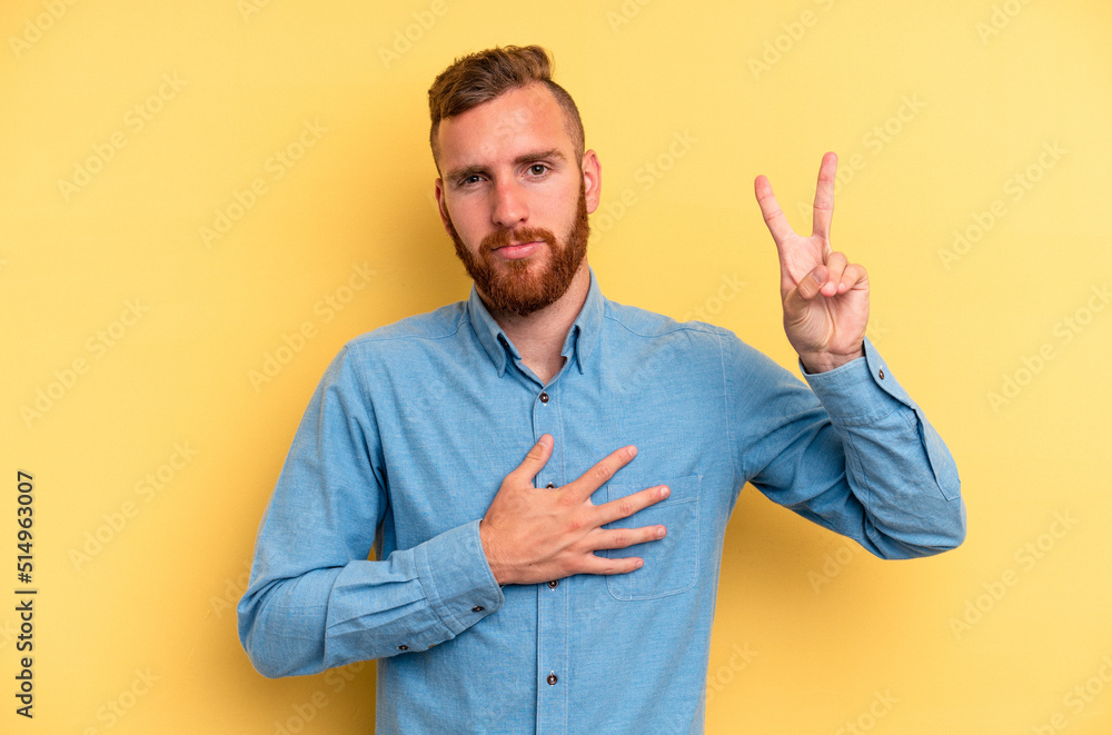 Young caucasian man isolated on yellow background taking an oath, putting hand on chest. Young caucasian man isolated on yellow background taking an oath, putting hand on chest.