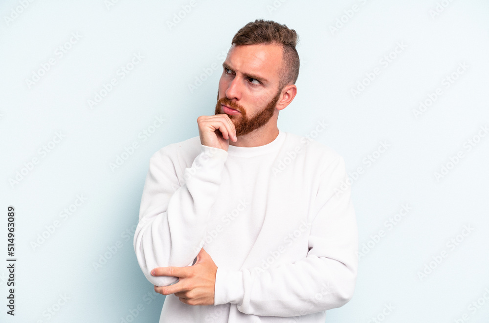 Young caucasian man isolated on blue background thinking and looking up, being reflective, contemplating, having a fantasy. Young caucasian man isolated on blue background thinking and looking up, being reflective, contemplating, having a fantasy.