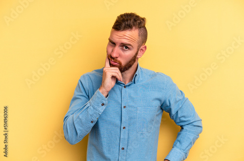 Young caucasian man isolated on yellow background contemplating, planning a strategy, thinking about the way of a business.