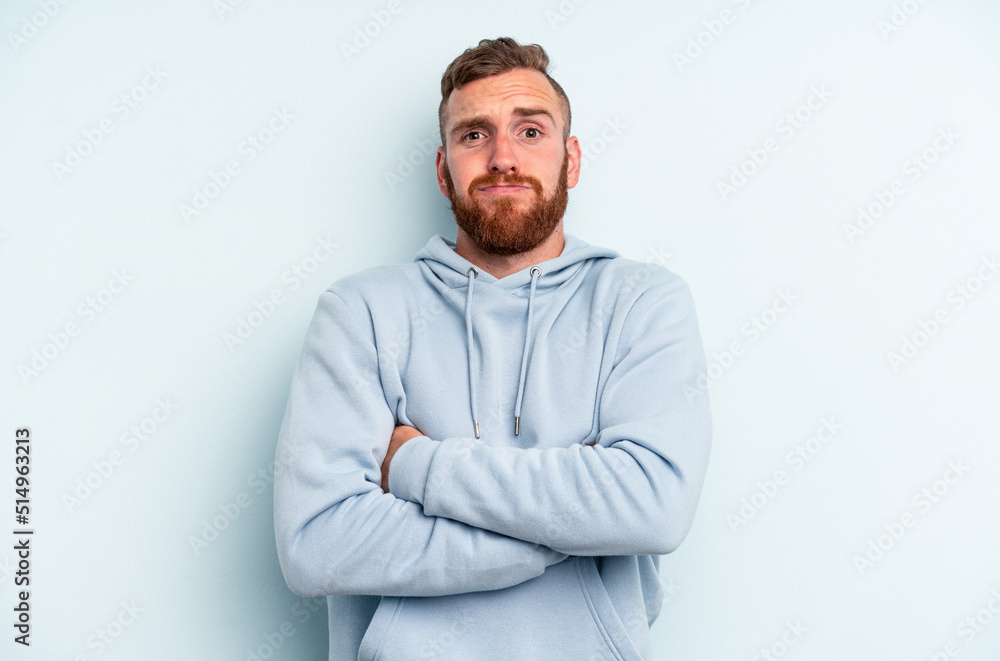Young caucasian man isolated on blue background blows cheeks, has tired expression. Facial expression concept. Young caucasian man isolated on blue background blows cheeks, has tired expression. Facial expression concept.