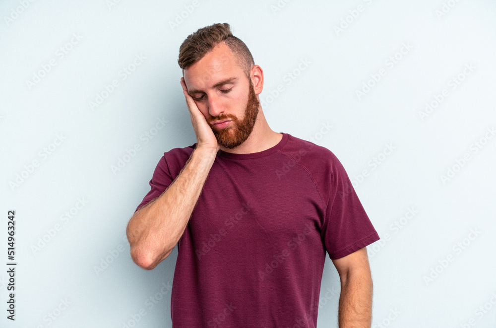 Young caucasian man isolated on blue background who is bored, fatigued and need a relax day. Young caucasian man isolated on blue background who is bored, fatigued and need a relax day.