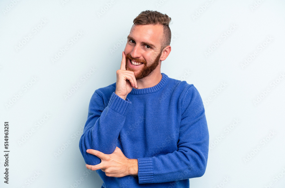 Young caucasian man isolated on blue background smiling happy and confident, touching chin with hand. Young caucasian man isolated on blue background smiling happy and confident, touching chin with hand.