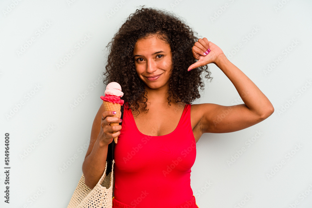 Young brazilian woman going to the beach holding an ice cream isolated on blue background feels proud and self confident, example to follow. Young brazilian woman going to the beach holding an ice cream isolated on blue background feels proud and self confident, example to follow.