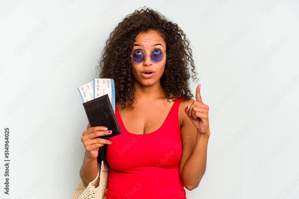 Naklejka premium Young brazilian woman wearing a swimsuit isolated on blue background pointing upside with opened mouth.