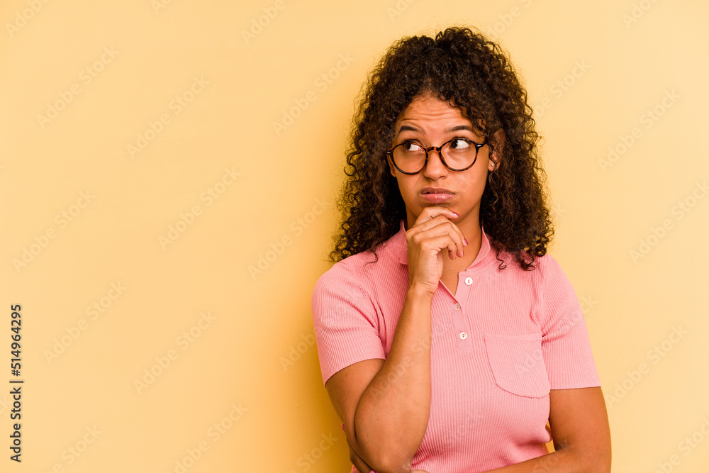 Young Brazilian woman isolated on yellow background looking sideways with doubtful and skeptical expression. Young Brazilian woman isolated on yellow background looking sideways with doubtful and skeptical expression.