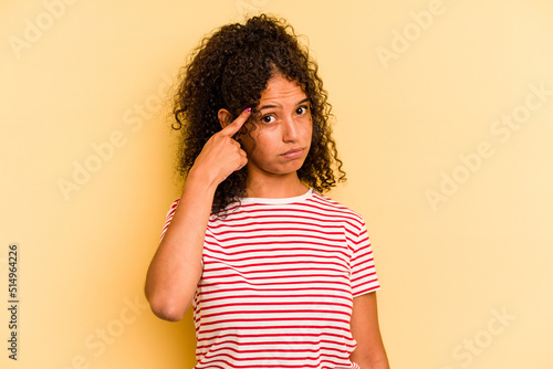 Young Brazilian woman isolated on yellow background pointing temple with finger, thinking, focused on a task.