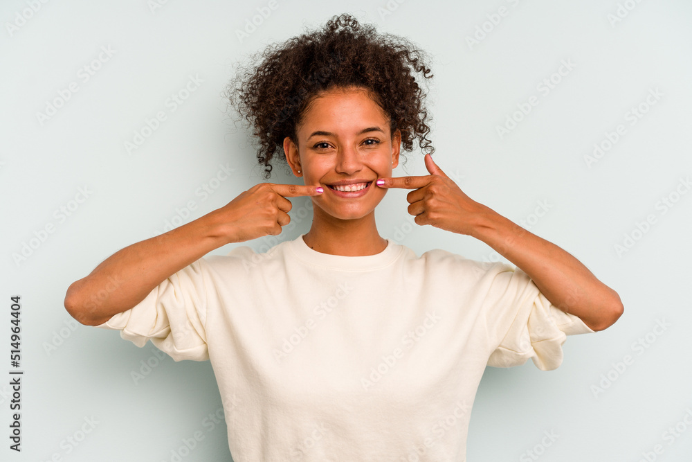 Young Brazilian woman isolated on blue background smiles, pointing fingers at mouth. Young Brazilian woman isolated on blue background smiles, pointing fingers at mouth.