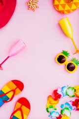 Flat lay of summer vibes concept with colorful pool party items, funny sunglasses, cocktail glasses. inflatable drink holders, flip flops, bucket hat, flower necklaces on pink background. Copy space.