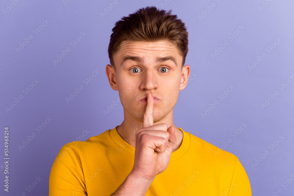 Photo of young man finger cover lips shh confidential keep secret isolated over violet color background Photo of young man finger cover lips shh confidential keep secret isolated over violet color background