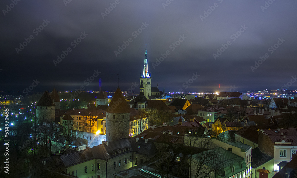 Town illuminated in evening twilight and St. Olaf Baptist Church, sea and port in Tallinn, Estonia