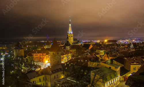 Town illuminated in evening twilight and St. Olaf Baptist Church, sea and port in Tallinn, Estonia 