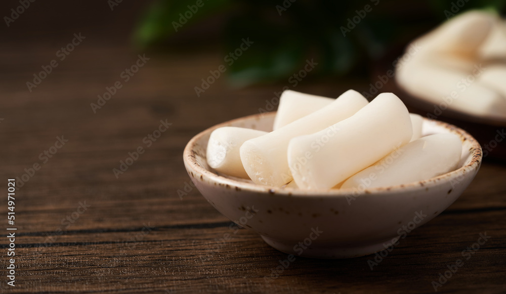 Tteok or Korean Rice Cakes in a dish on a wood background Tteok or Korean Rice Cakes in a dish on a wood background