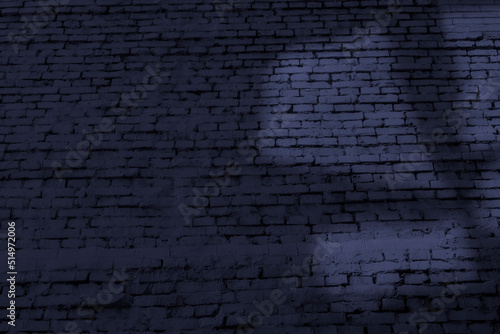 Old brick wall with abstract light shape at dark evening time. Blue background image with copy space