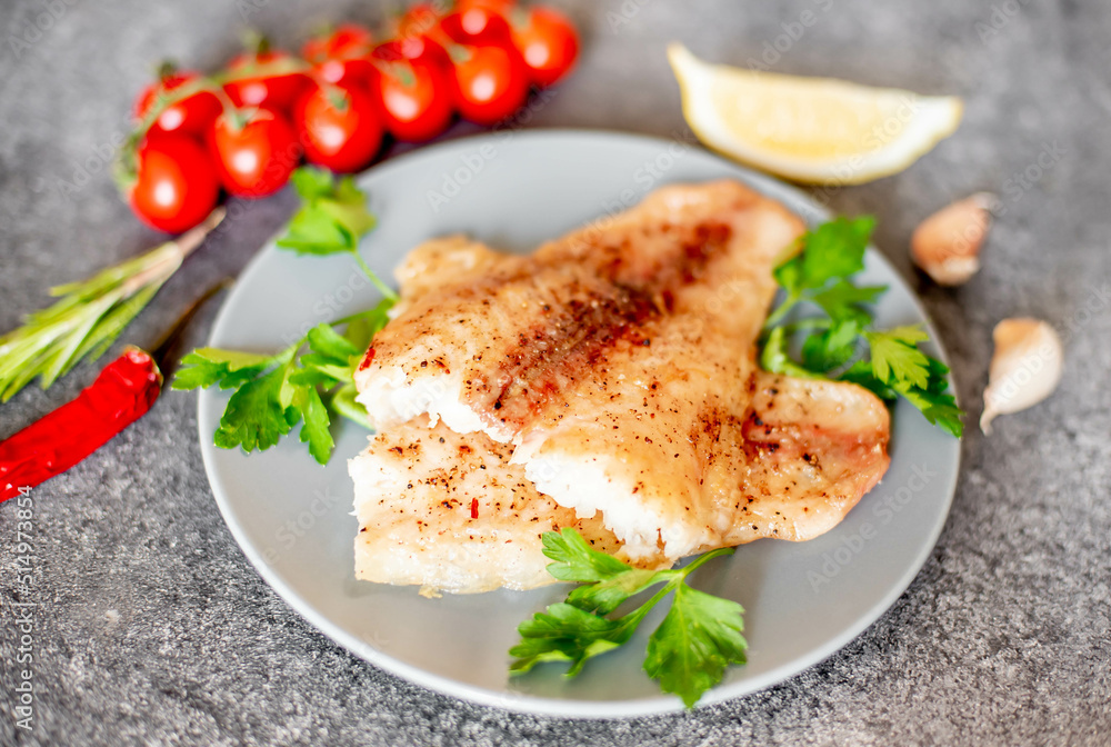 Baked white fish fillet Pangasius with spices and lemon on a stone background Baked white fish fillet Pangasius with spices and lemon on a stone background