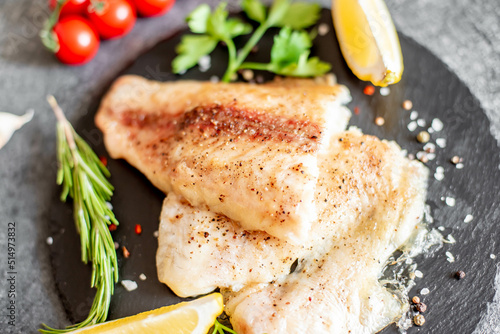 Photography Baked white fish fillet Pangasius with spices and lemon on a stone background