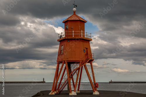 The old, red, wooden Herd Groyne Lighthouse in South Shields, stands out against the cloudy sky
 photo
