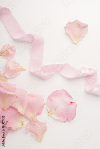 Close-up of a velvet ribbon on a light background with details of flowers. Pink ribbon next to the petals