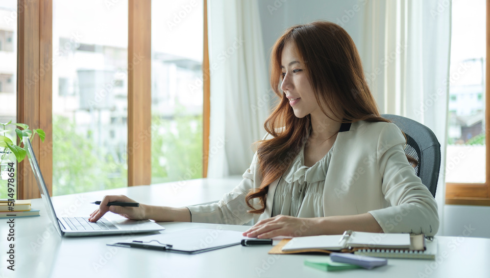 Millennial businesswoman sitting in bright office and using laptop computer. Millennial businesswoman sitting in bright office and using laptop computer.