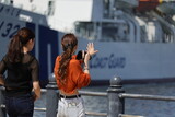 横浜港で船の写真を撮る女性