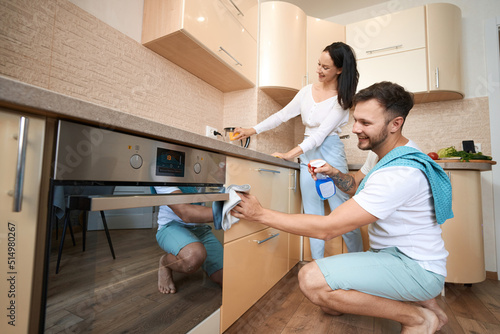 Husband and wife cleaning kitchen together with detergent photo