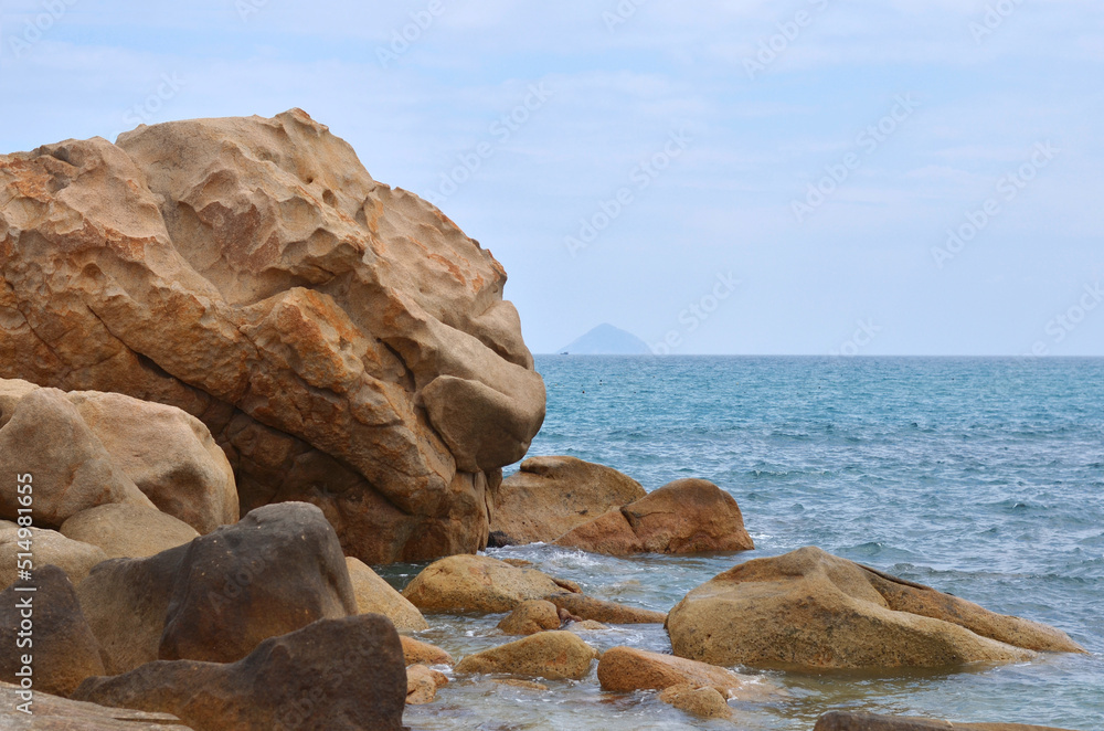 Fototapeta premium Rocks on the beach. Seashore landscape with big yellow color natural stones in the water. Summer holidays near the sea, travelling concept.