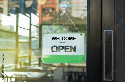 "Welcome we are open" label in front of glass door at the coffee shop to notice customer service